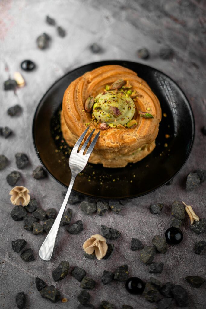 pexels-photo-31846711-31846711 A beautifully presented pistachio cake topped with nuts and a fork, styled on a textured surface.